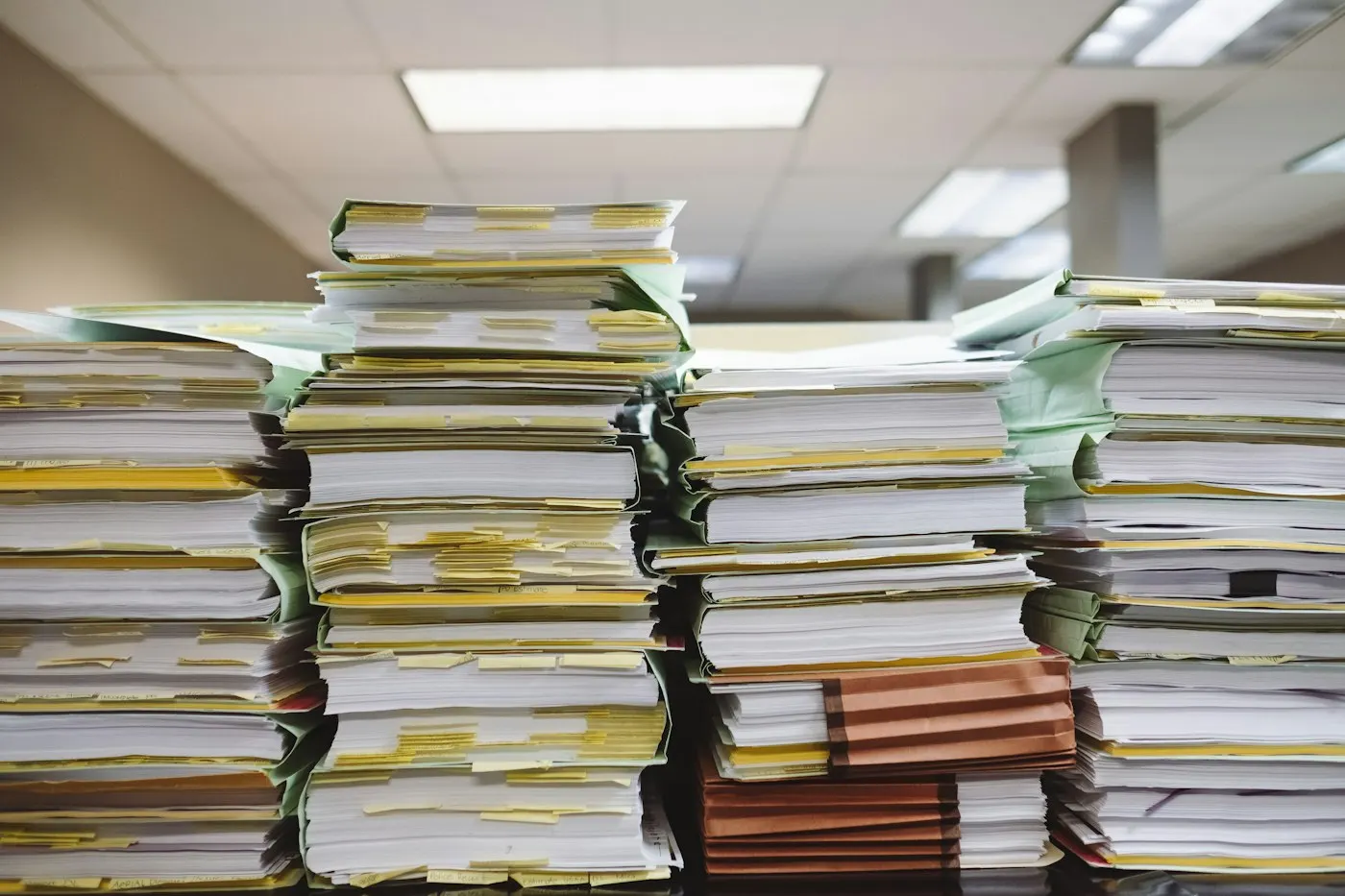 A stack of paper folders stacked on a wooden desk