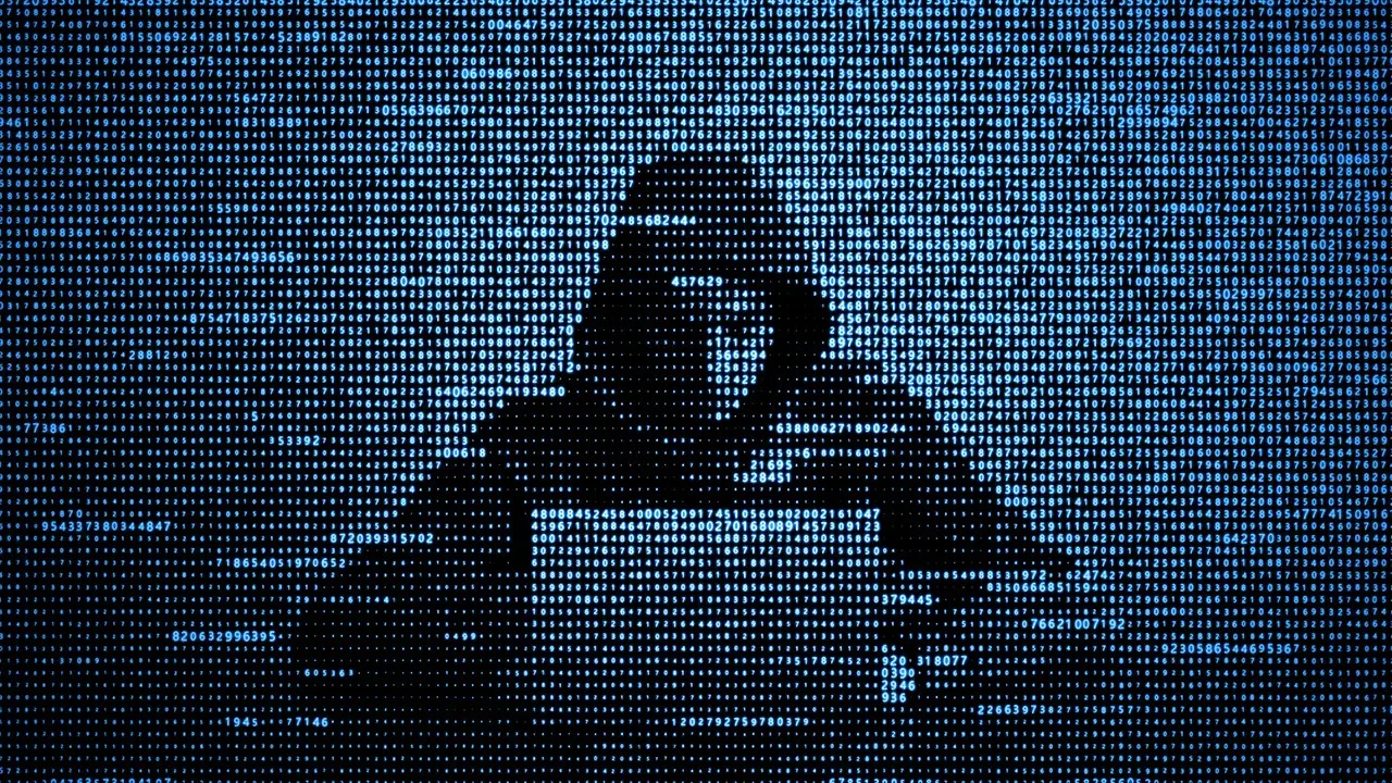 A person at a computer screen displaying network data and code, representing the scale of modern cybercrime
