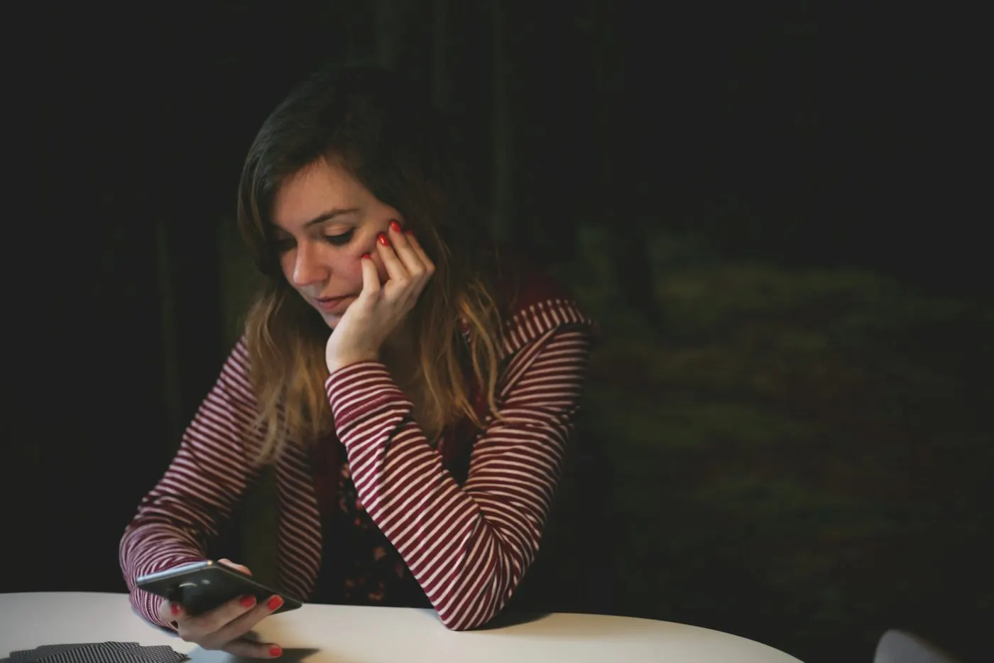 A teenager looking at a smartphone in a dark room