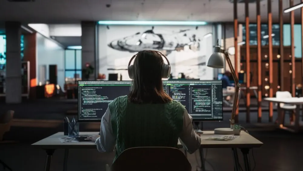 A developer working alongside AI-generated code on a laptop screen.