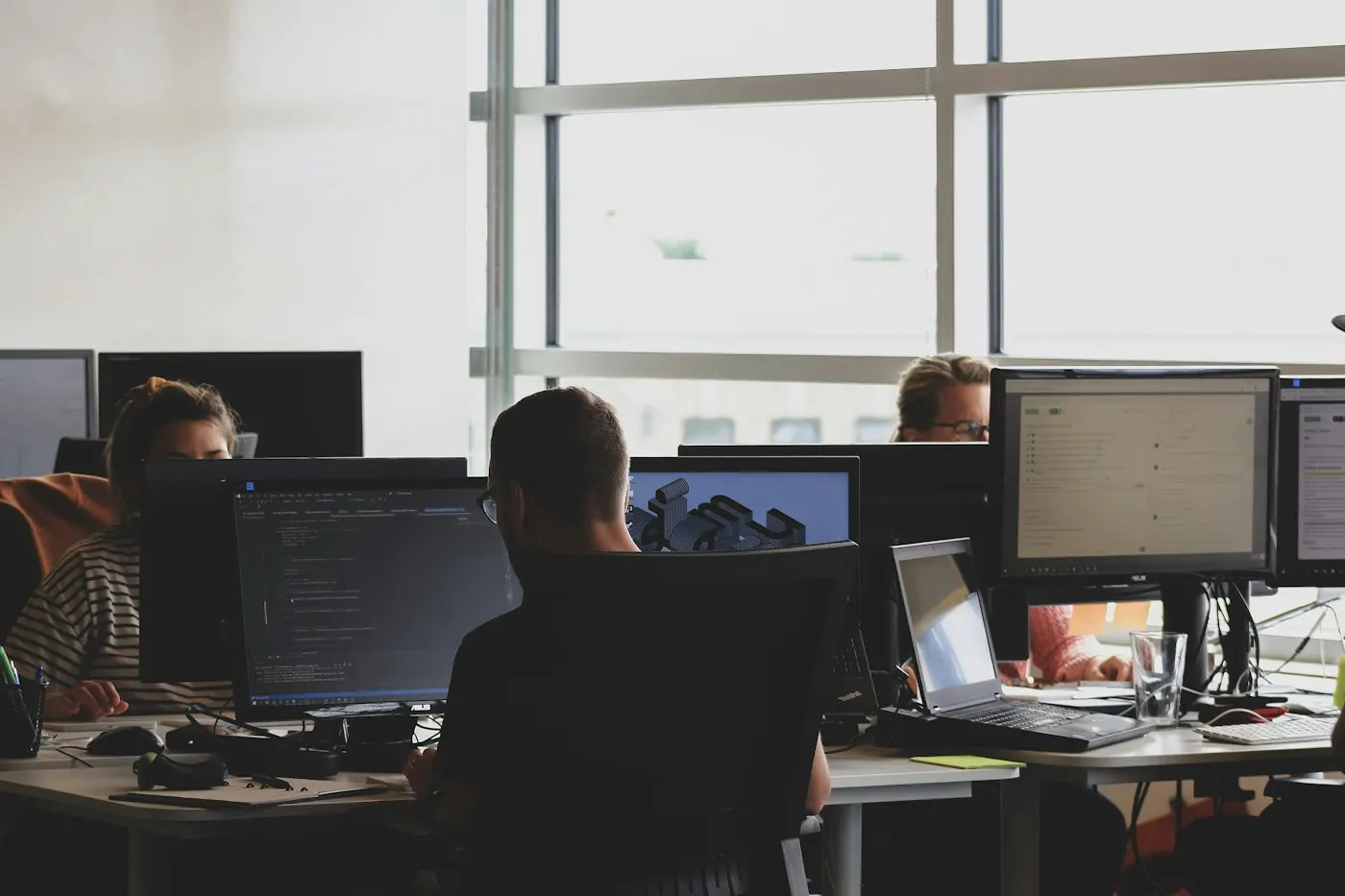 A team reviewing code together on a monitor in an office