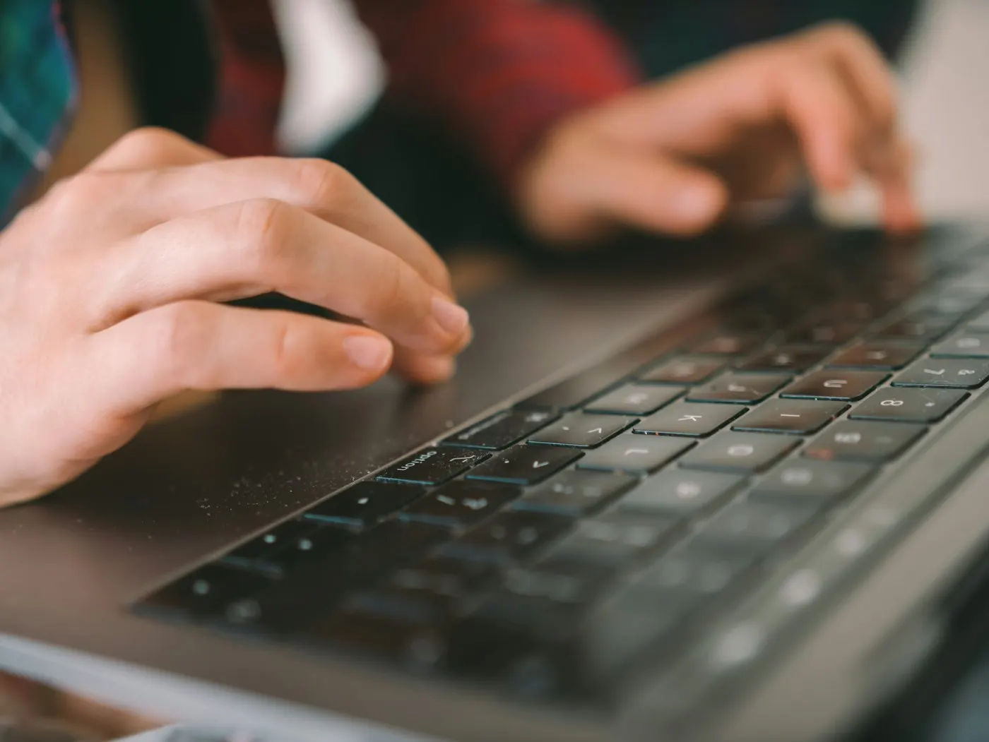Close-up of hands typing on a laptop keyboard