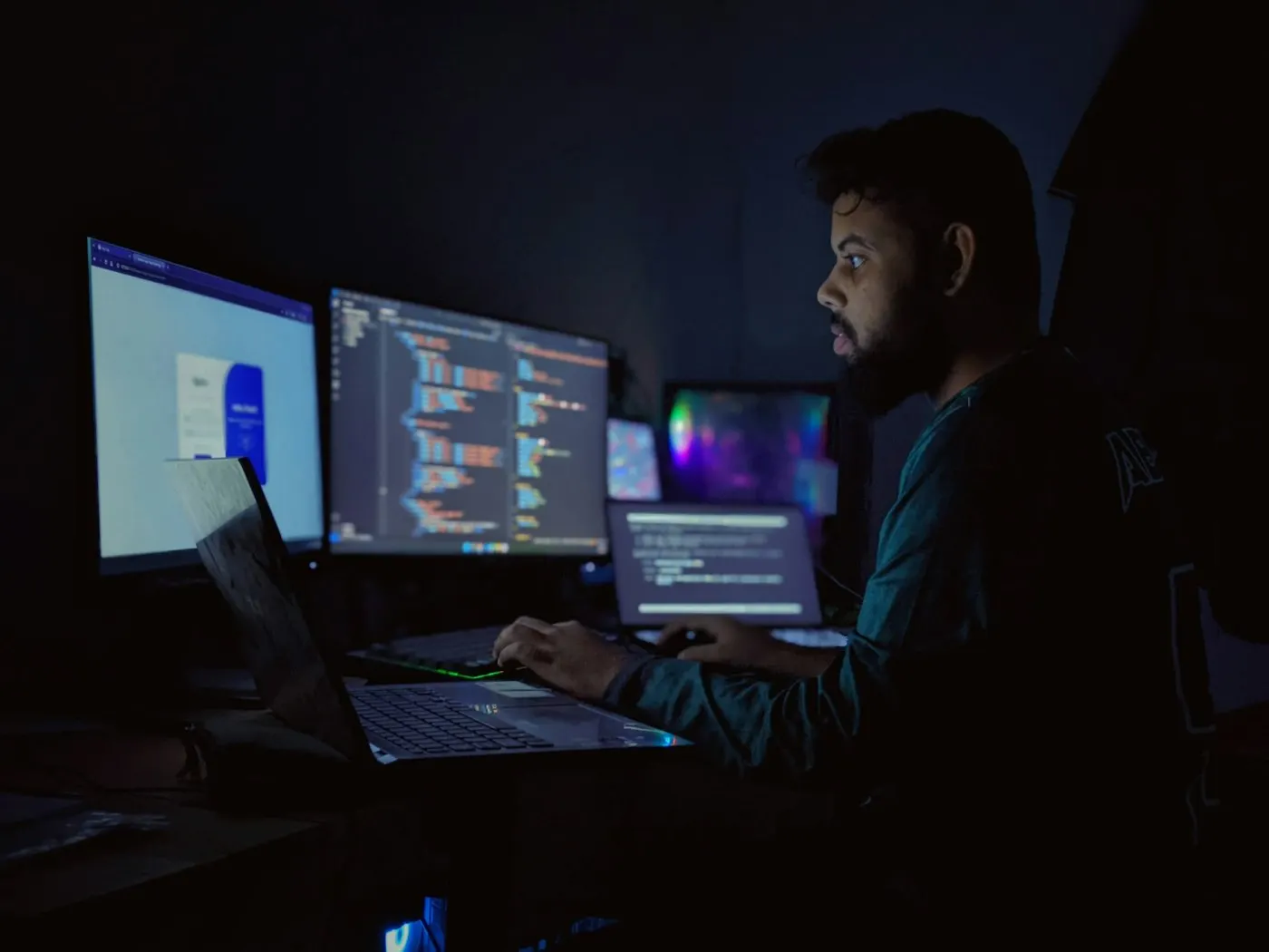 A software developer's monitor glowing in a dim room