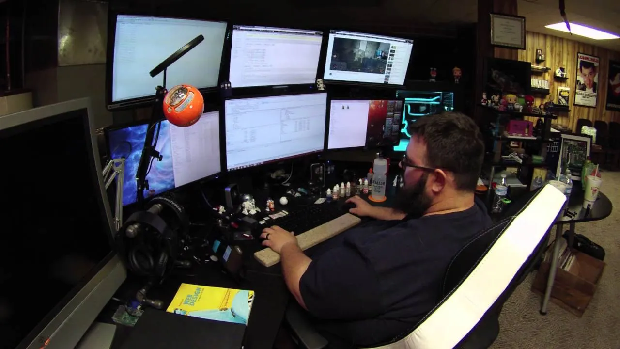 A web developer working at a multi-monitor setup showing code editors and an AI coding assistant.