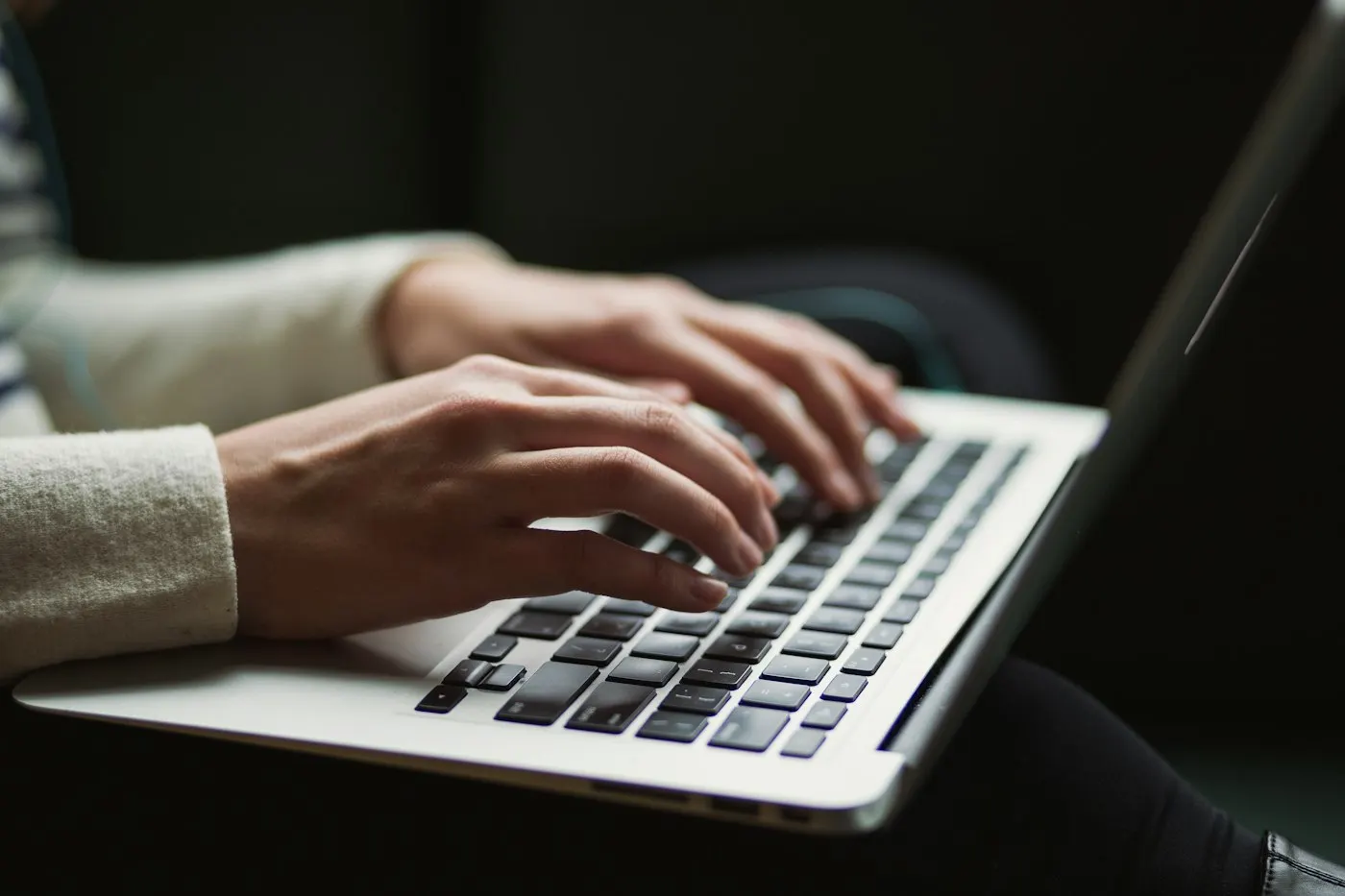 Person typing on a laptop keyboard at night