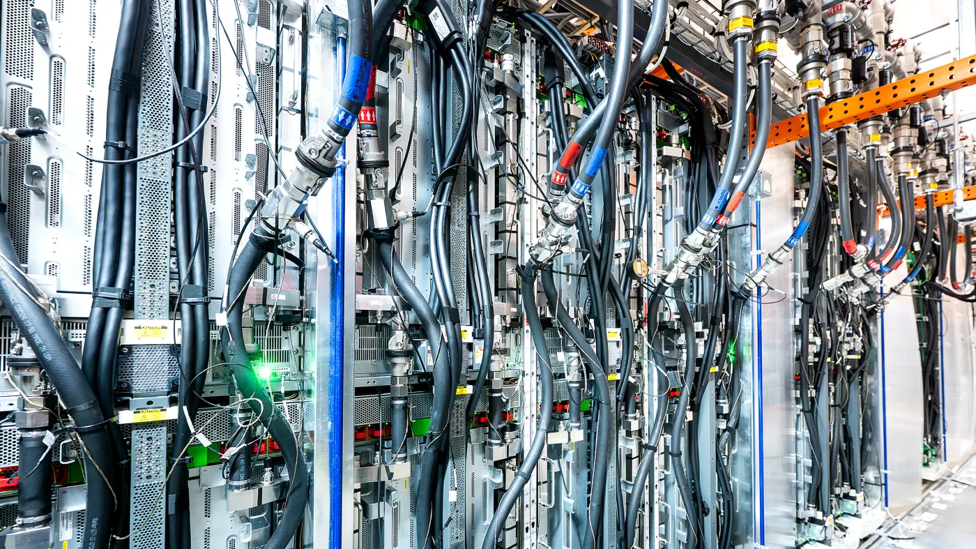 Industrial liquid cooling towers and pipework outside a data center, illustrating the large volumes of water used to cool AI computing hardware