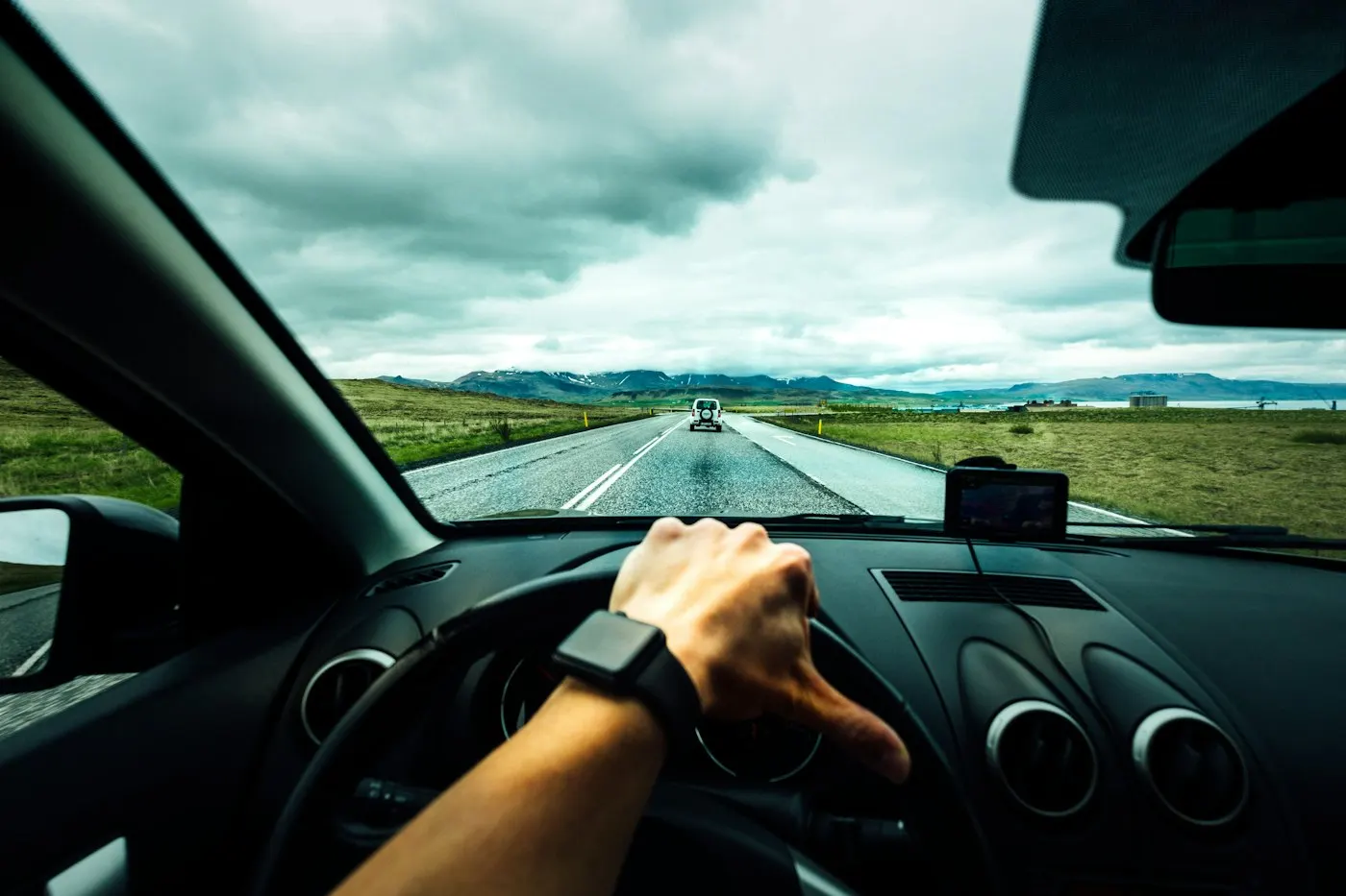 A driver's hands resting on a car steering wheel